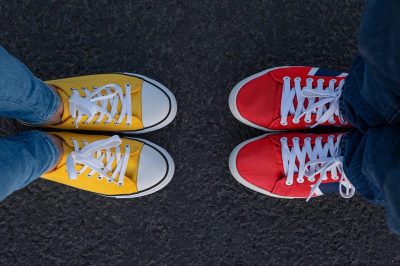 Man and woman of red and yellow sneakers stand opposite each other on a asphalt background, the top view.